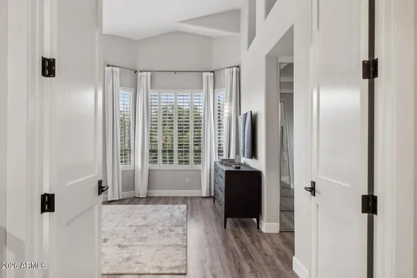 a bedroom with a bed a large window with table and chair