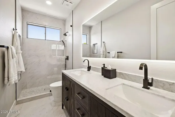 a bedroom with a bed and a lamp on dresser