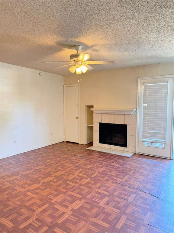 9815 Walnut Street, Unit 102 Dallas, TX 75243 - Photo 11 of 13 Living space featuring a fireplace with a tiled hearth and mantel, wood-finish flooring, and a ceiling fan with integrated lighting