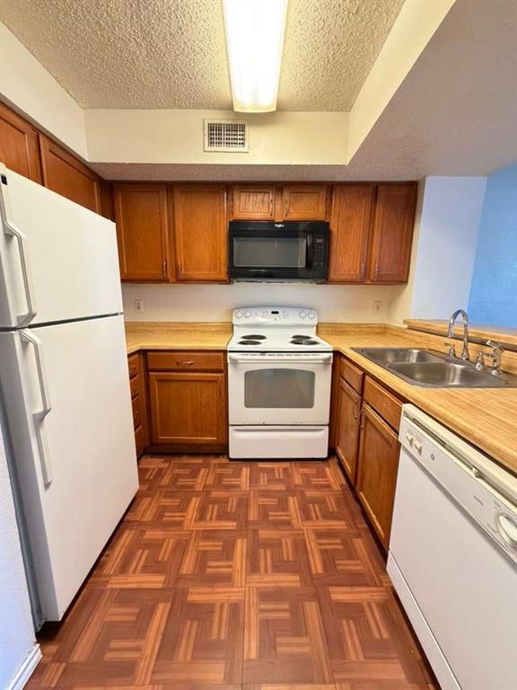 9815 Walnut Street, Unit 102 Dallas, TX 75243 - Photo 5 of 13 Kitchen featuring wood-finish cabinetry, patterned wood-finish flooring, and light wood-finish countertops