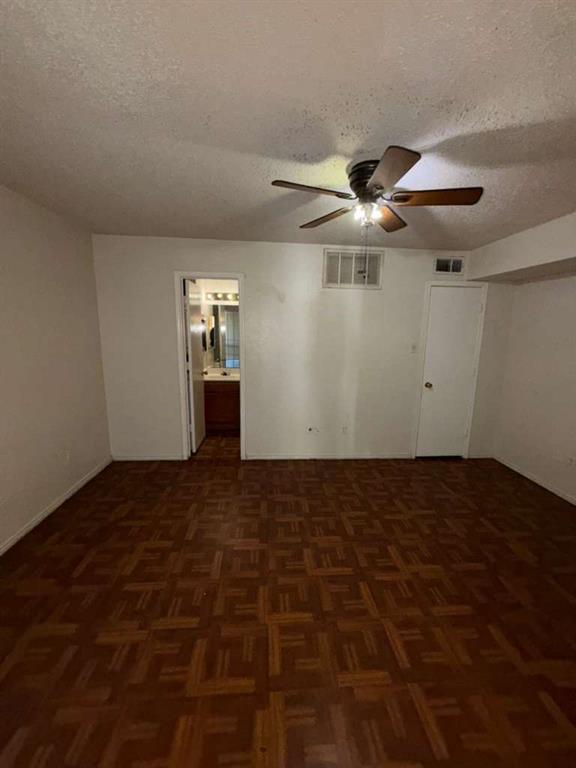 9815 Walnut Street, Unit 102 Dallas, TX 75243 - Photo 9 of 13 Spacious room featuring patterned wood-finish flooring, a ceiling fan with light fixture, and white painted walls