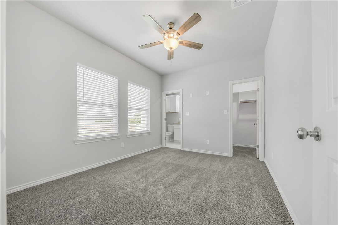 1805 Pin Oak Street Bryan, TX 77803 - Photo 3 of 20 Unfurnished bedroom featuring carpet flooring, a spacious closet, ensuite bathroom, and a ceiling fan