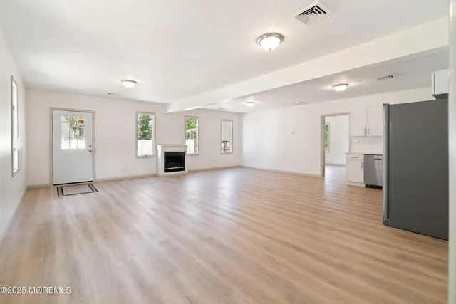 a view of an empty room with wooden floor and entryway
