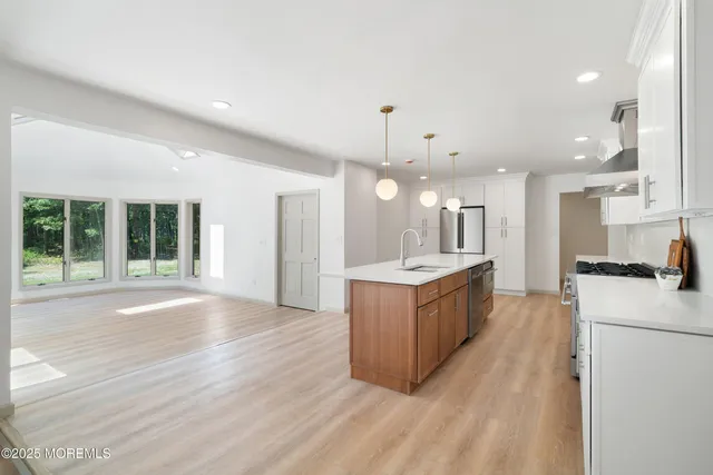 a kitchen with stainless steel appliances granite countertop a stove a sink and a wooden floors