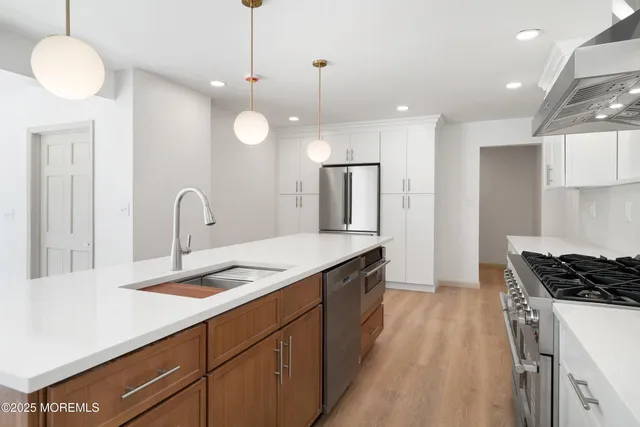 a large kitchen with kitchen island a sink stainless steel appliances and a large window