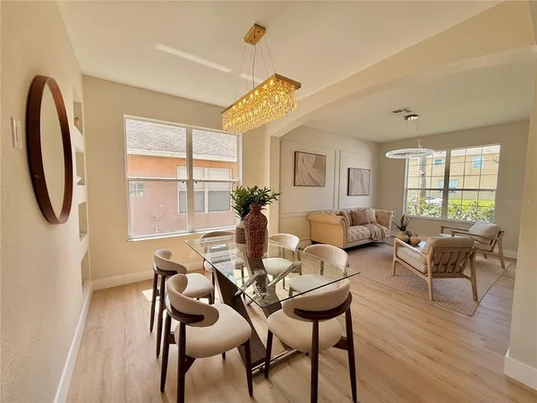 a kitchen with stainless steel appliances a dining table chairs refrigerator and microwave