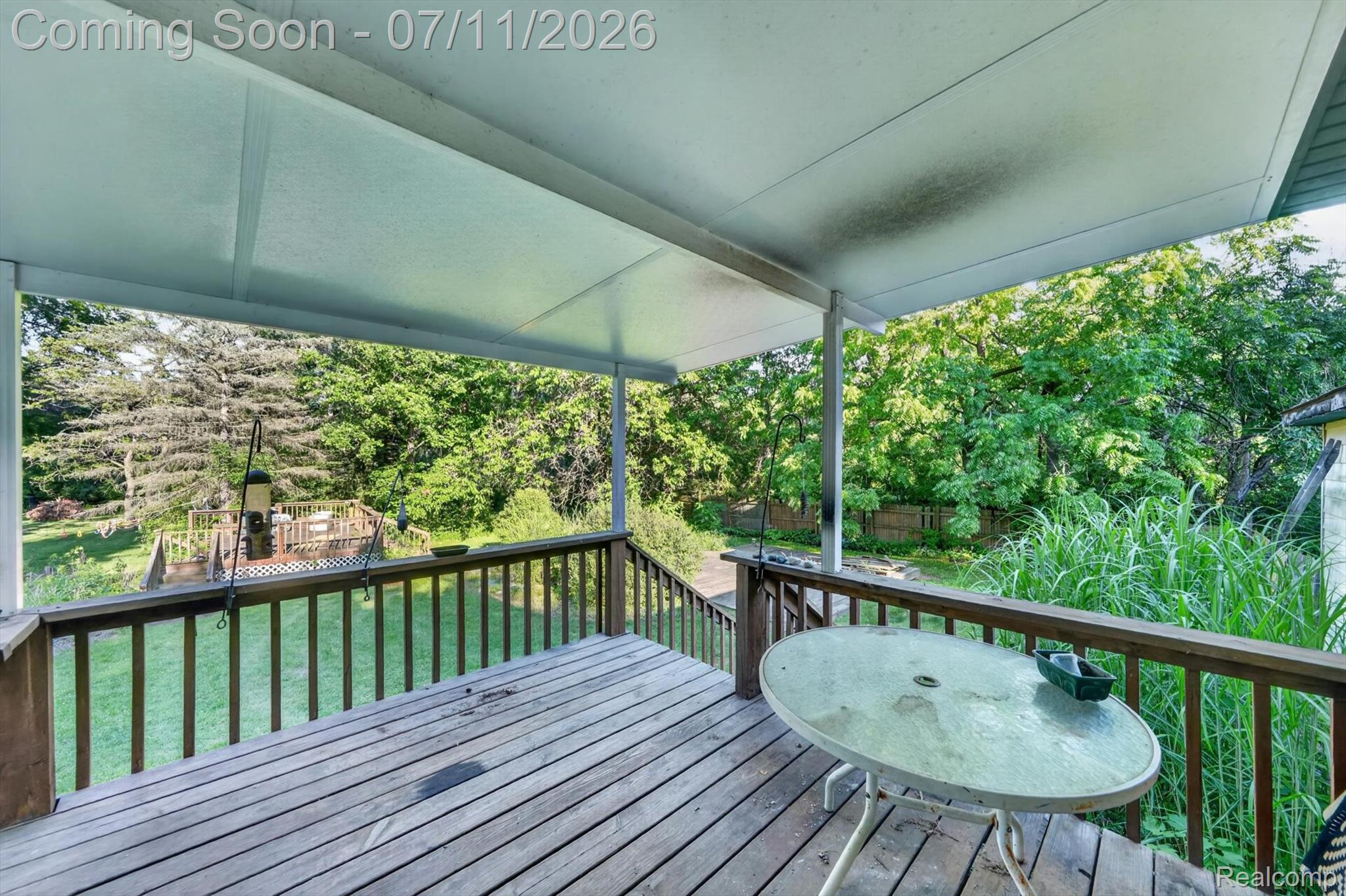 4430 North Center Road Flint, MI 48506 - Photo 48 of 49 Covered wooden deck with slatted flooring, featuring a railing system and steps descending to a lower wooden platform