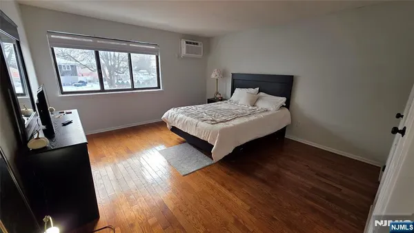 a bedroom with wooden floor and window