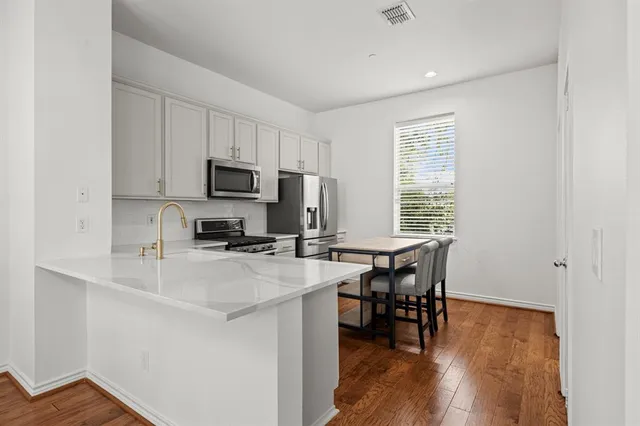 a kitchen with a table chairs microwave and cabinets