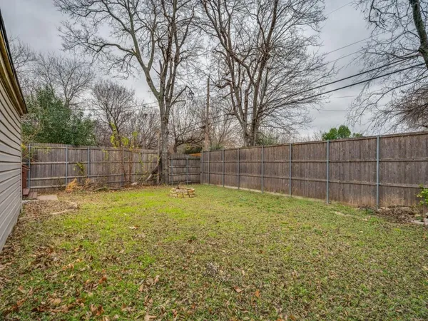 a view of a backyard with a large tree and wooden fence