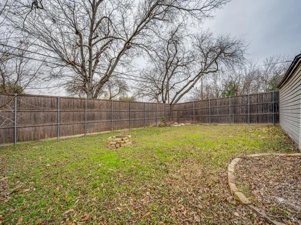 a view of a backyard with a large tree and wooden fence