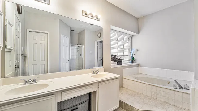 a bathroom with a tub a sink and a large mirror