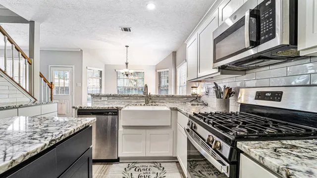 a kitchen with kitchen island granite countertop a sink stove and cabinets