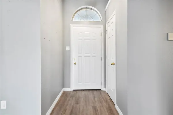 an empty room with wooden floor cabinet and a mirror
