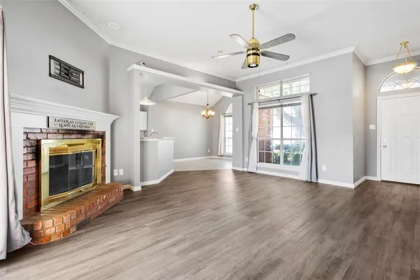 a view of an empty room with wooden floor and a fireplace