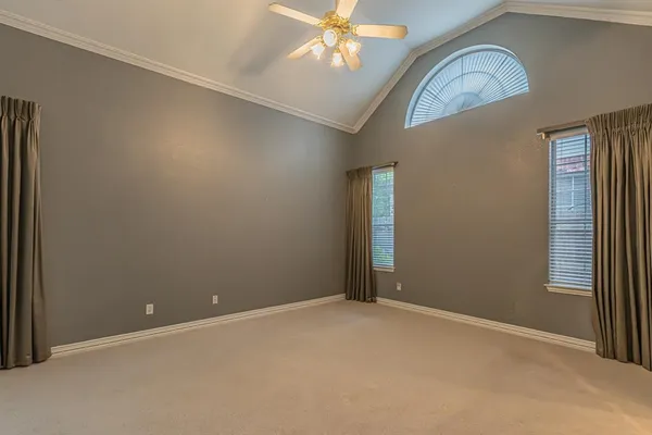 an empty room with chandelier fan and windows