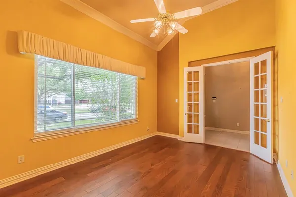 a view of an empty room with wooden floor and a window
