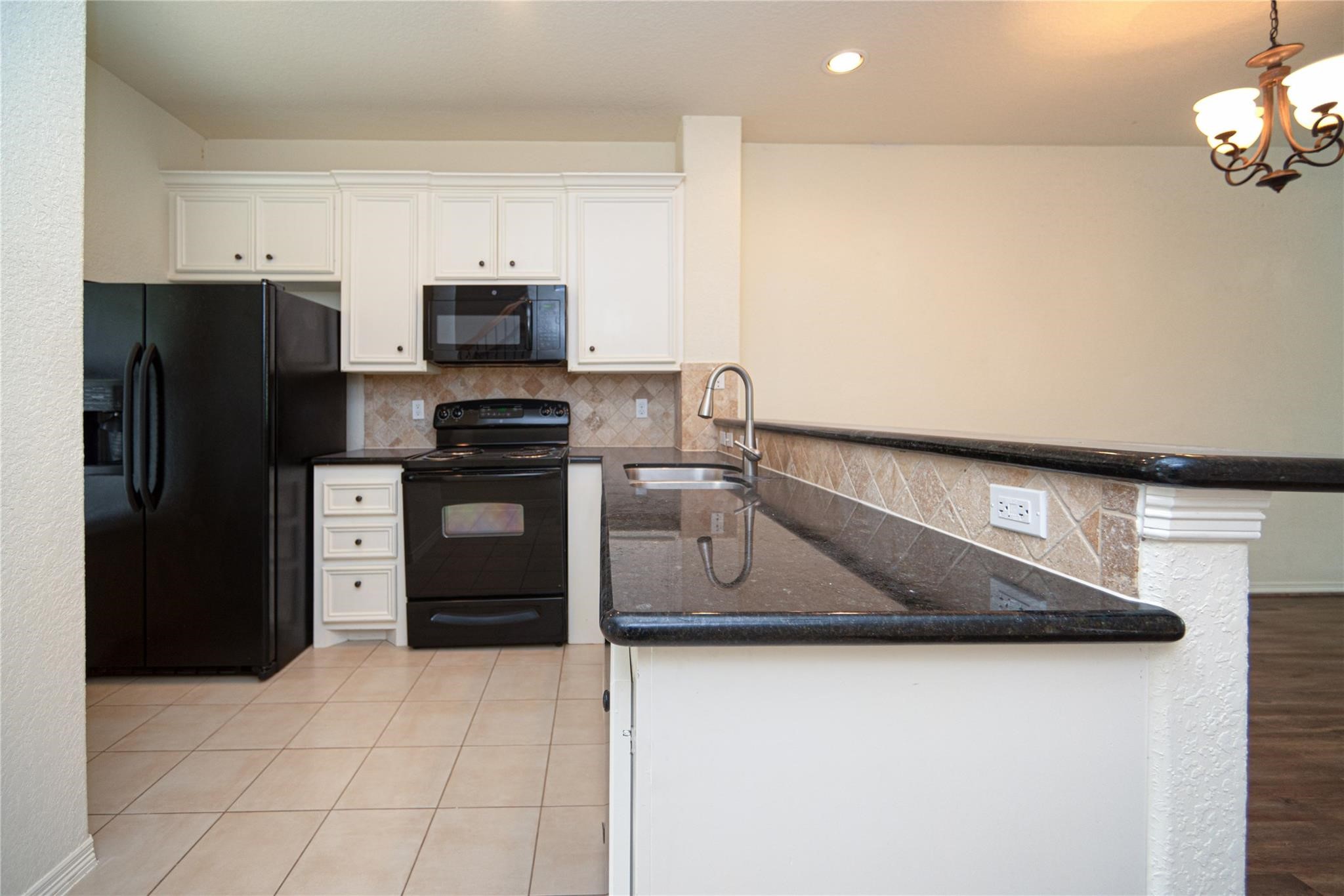 1426 April Villas, Unit A Conroe, TX 77356 - Photo 5 of 8 a kitchen with stainless steel appliances granite countertop a refrigerator a stove and a sink