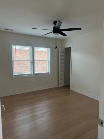 a view of an empty room with wooden floor and window