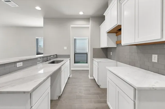 a kitchen with granite countertop a sink and dishwasher a stove top oven with white cabinets