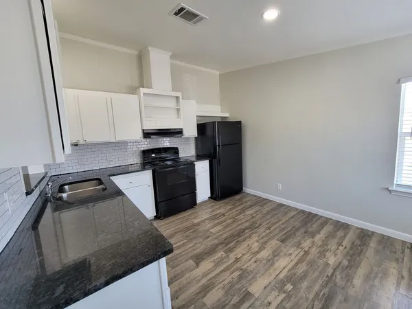 a kitchen with granite countertop a refrigerator sink and stove