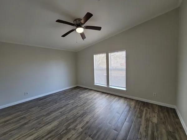 a view of empty room with wooden floor and fan