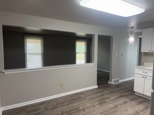 an empty room with wooden floor and cabinet