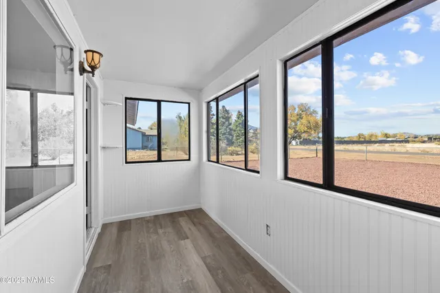an empty room with wooden floor ceiling fan and windows