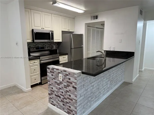 a kitchen with granite countertop a refrigerator and a stove top oven