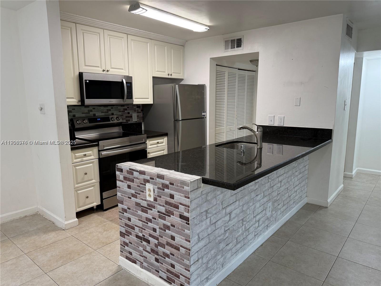 10421 Southwest 157th Place, Unit 206 Miami, FL 33196 - Photo 35 of 35 a kitchen with granite countertop a refrigerator and a stove top oven