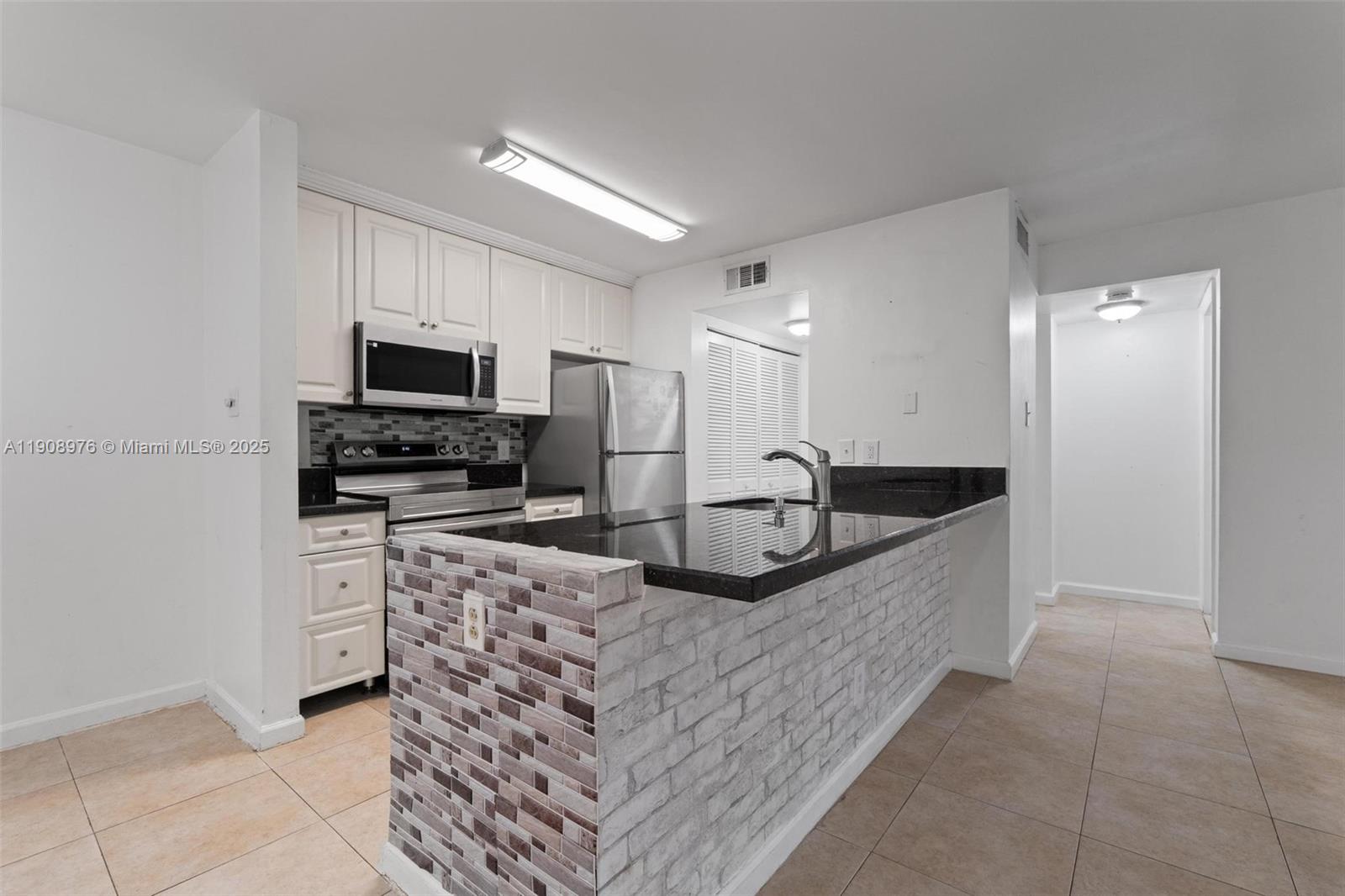 10421 Southwest 157th Place, Unit 206 Miami, FL 33196 - Photo 9 of 35 a large kitchen with kitchen island a sink stainless steel appliances and cabinets