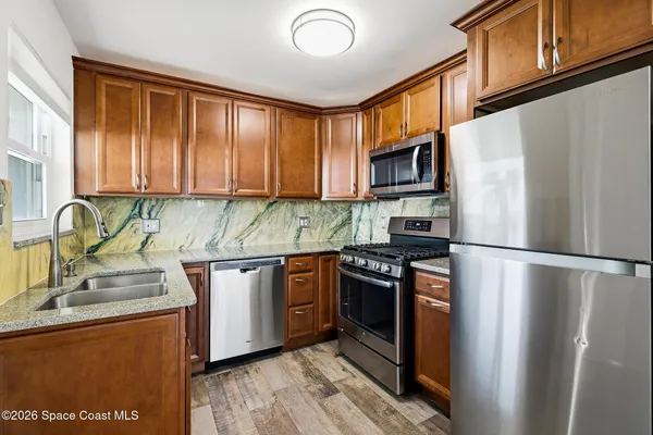 a kitchen with granite countertop a refrigerator stove top oven and sink