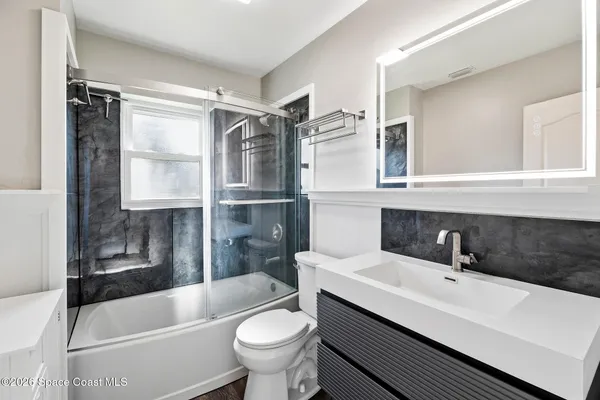 a bathroom with a sink a toilet a mirror and bathtub