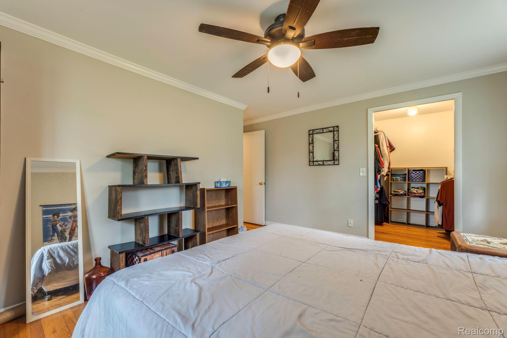 3560 North Road North Street, MI 48049 - Photo 41 of 53 Bedroom featuring a spacious closet, wood finished floors, crown molding, and ceiling fan