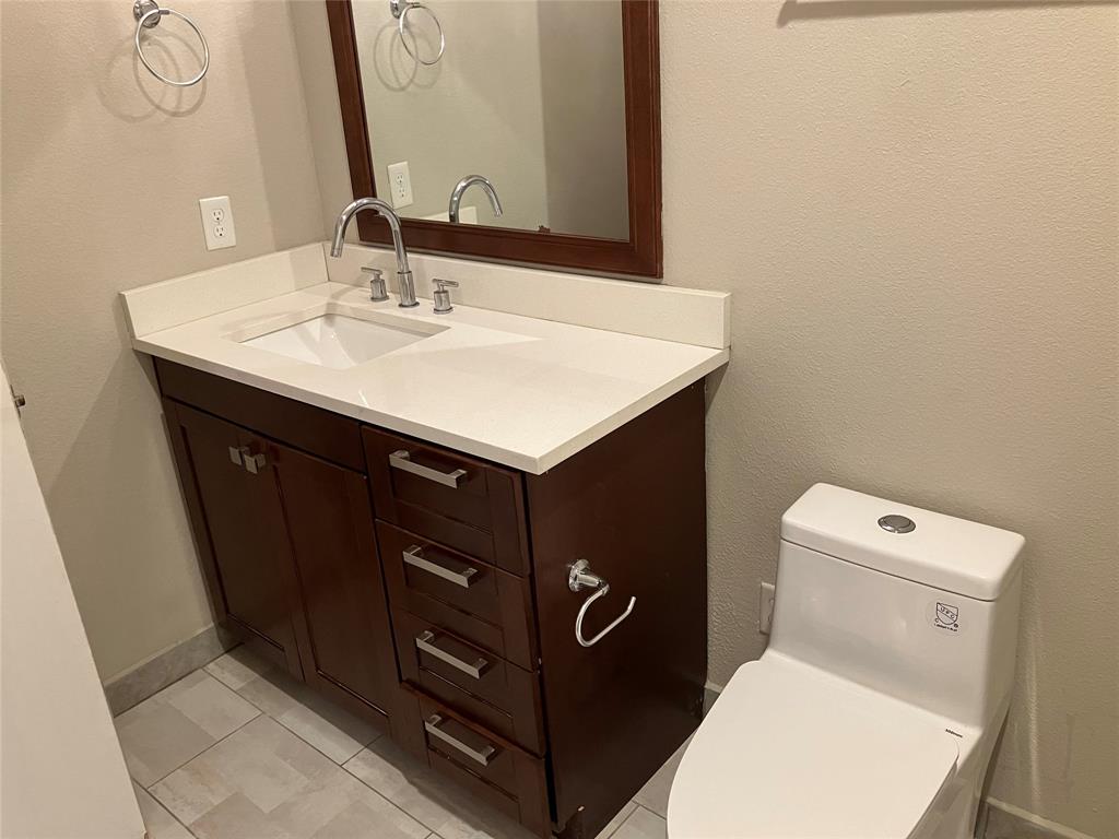 1220 West Trinity Mills Road, Unit 5009 Carrollton, TX 75006 - Photo 17 of 25 a bathroom with a sink vanity and a toilet