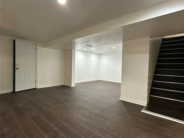 a view of an empty room with wooden floor and stairs