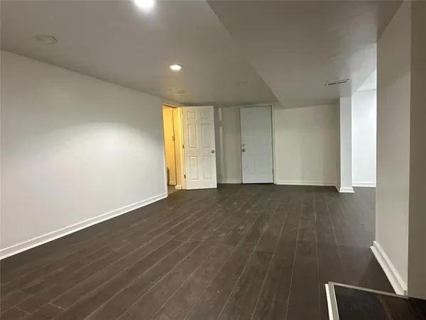 a view of an empty room with wooden floor and a cabinet