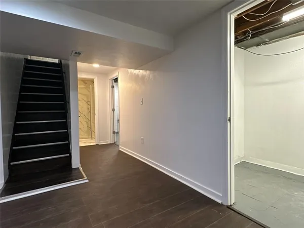 a view of an empty room with wooden floor and stairs