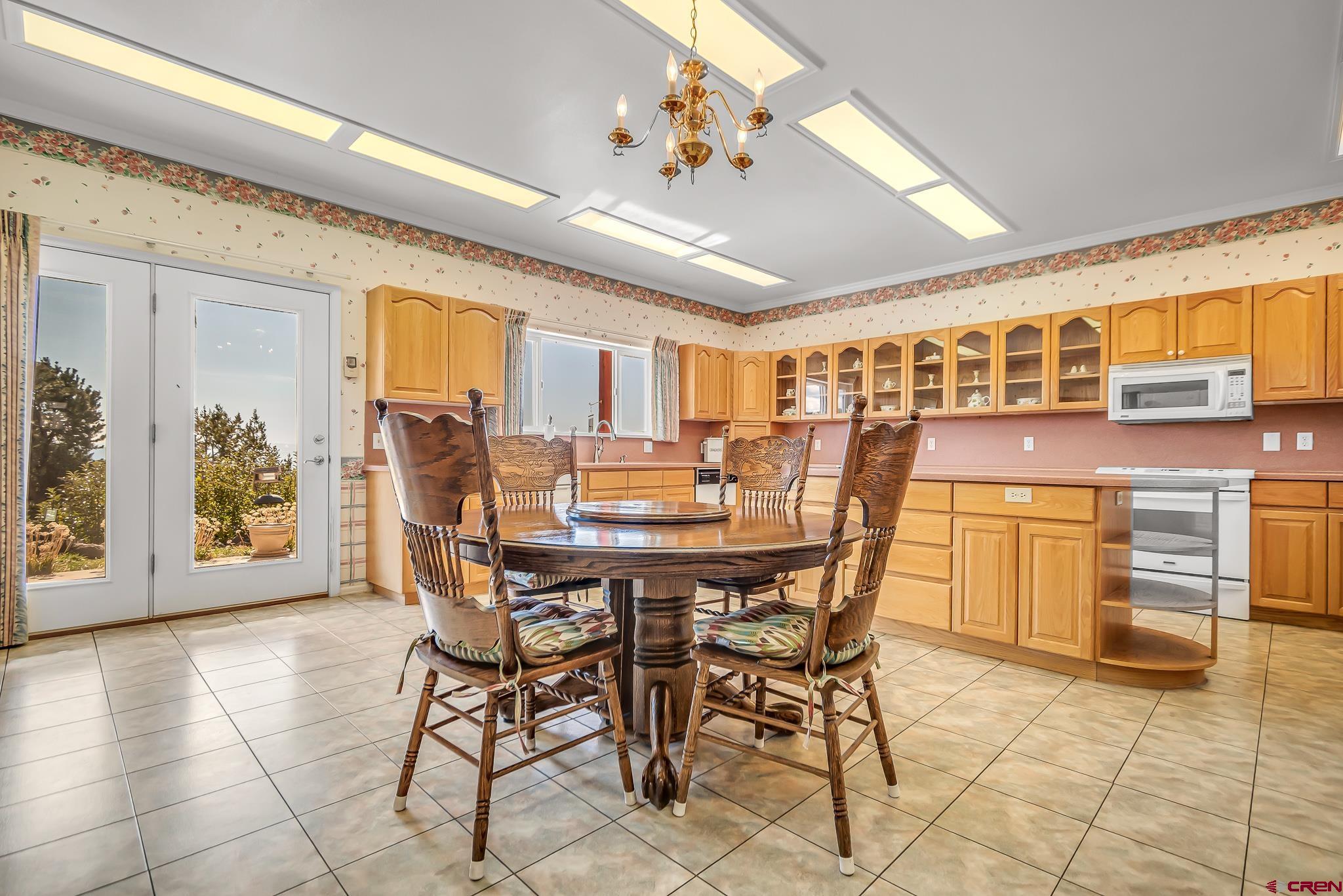 24344 Ute Trail Road Cedaredge, CO 81413 - Photo 15 of 33 a dining area with chandelier and kitchen view