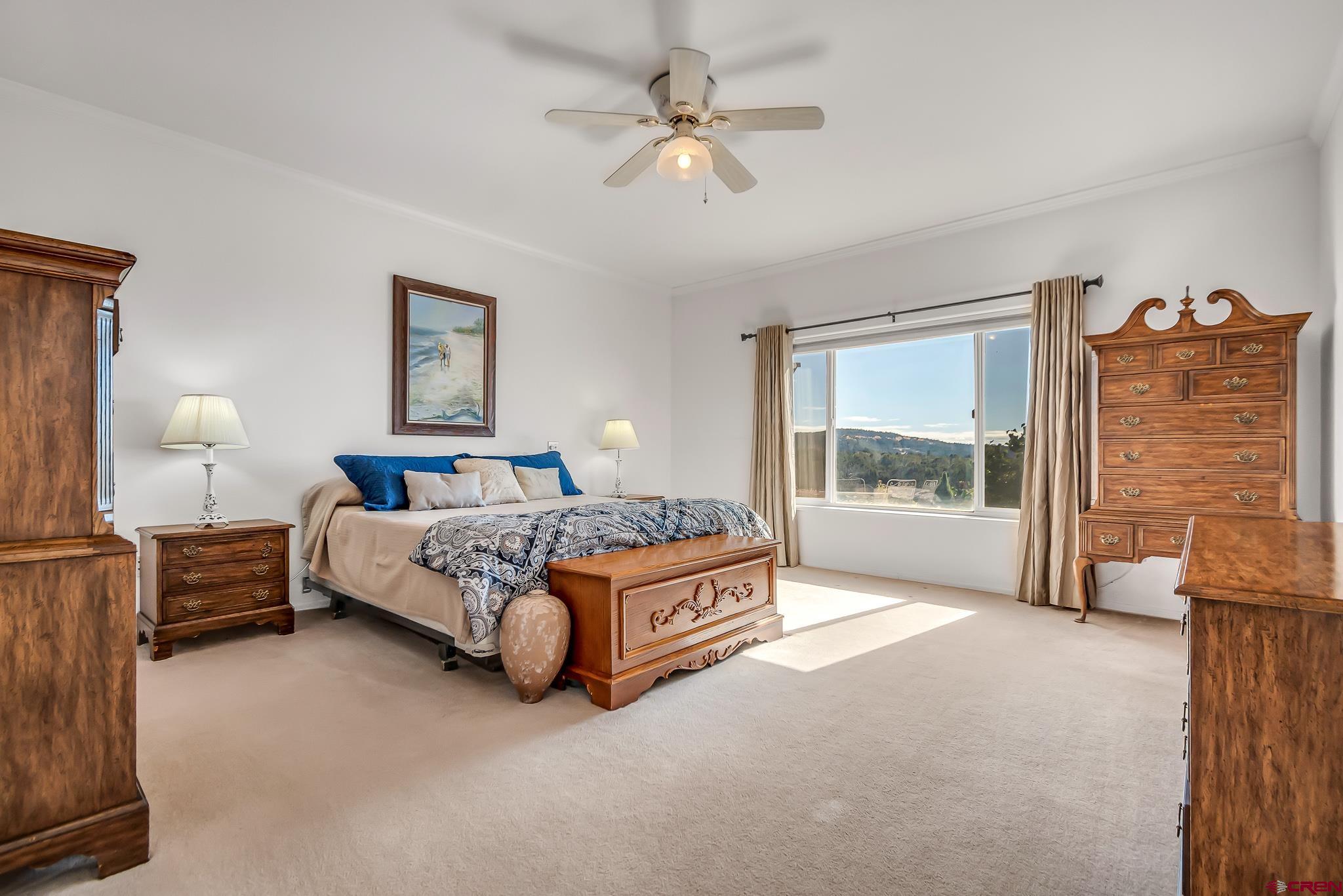 24344 Ute Trail Road Cedaredge, CO 81413 - Photo 26 of 33 a spacious bedroom with a bed and a chandelier