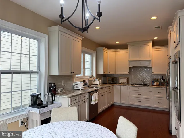 a kitchen with stainless steel appliances a sink a stove a refrigerator cabinets and a window