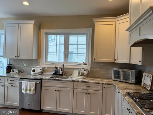 a kitchen with granite countertop a sink a stove and cabinets