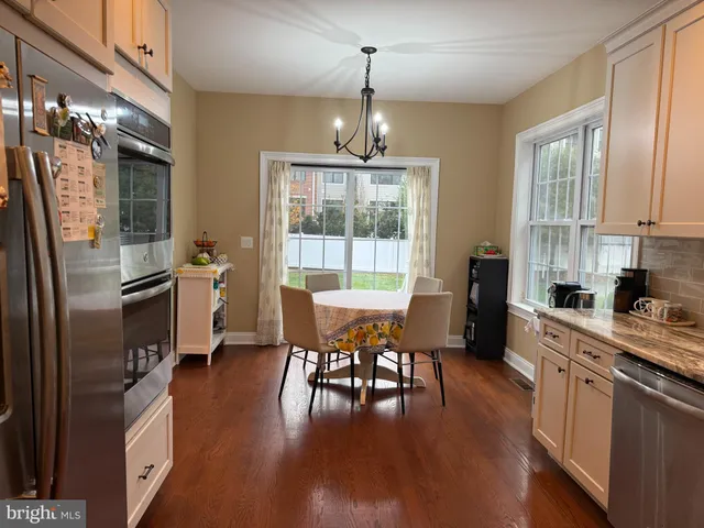 a kitchen with stainless steel appliances granite countertop a refrigerator a stove top oven a sink dishwasher and white cabinets with wooden floor