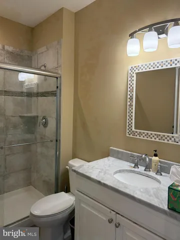 a bathroom with a granite countertop sink a toilet a mirror and shower