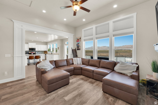 1857 Thunder Gulch Road Eagle Mountain, UT 84005 - Photo 8 of 50 Bright living area featuring expansive windows, wood-finish flooring, recessed lighting, a ceiling fan, and an architectural opening to the kitchen