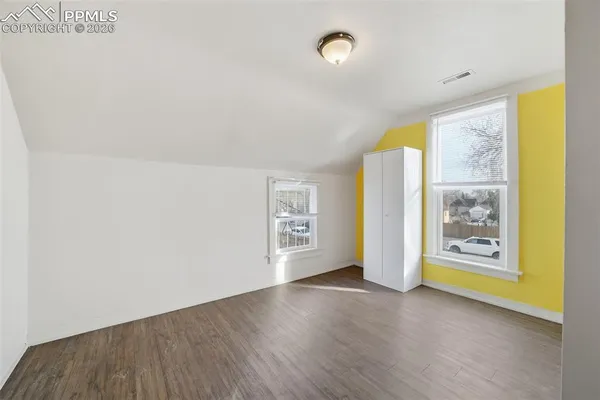 a view of an empty room with a window and wooden floor