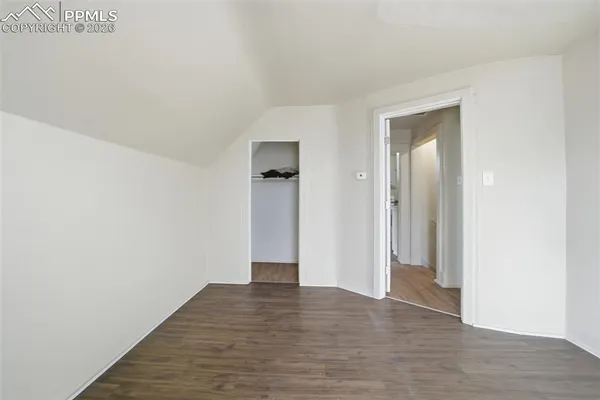 a view of an empty room with wooden floor and closet