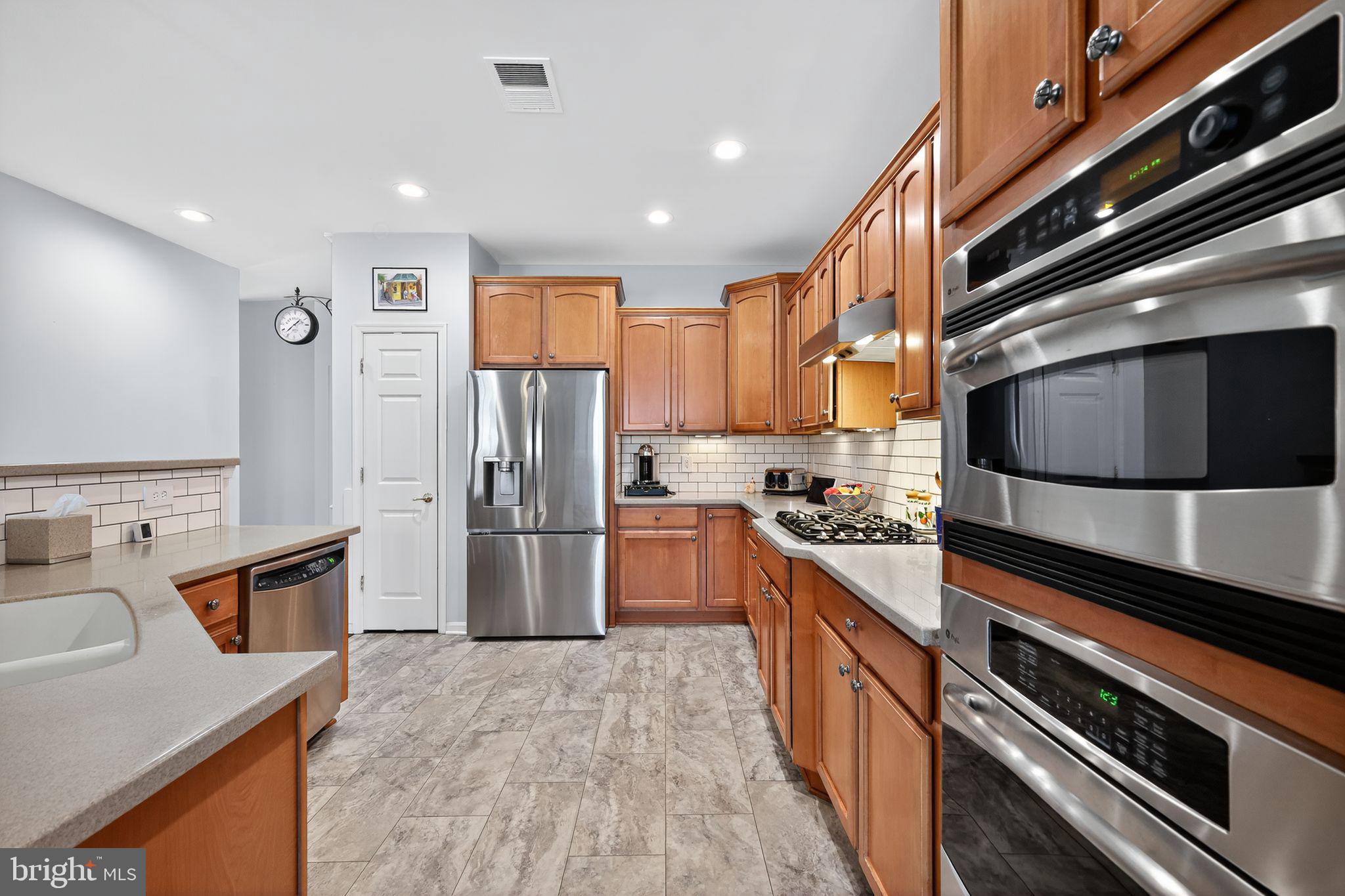 6013 Piney Grove Way Gainesville, VA 20155 - Photo 11 of 41 a kitchen with stainless steel appliances granite countertop a refrigerator and a stove top oven