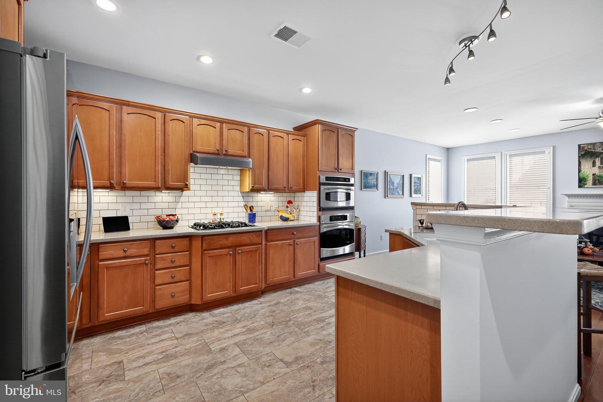 6013 Piney Grove Way Gainesville, VA 20155 - Photo 8 of 41 a kitchen with stainless steel appliances granite countertop a refrigerator sink and cabinets
