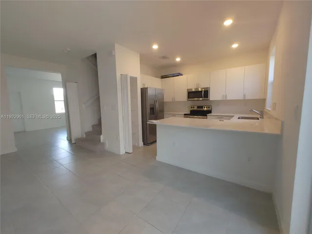 a view of a kitchen with a sink and dishwasher a refrigerator with wooden floor